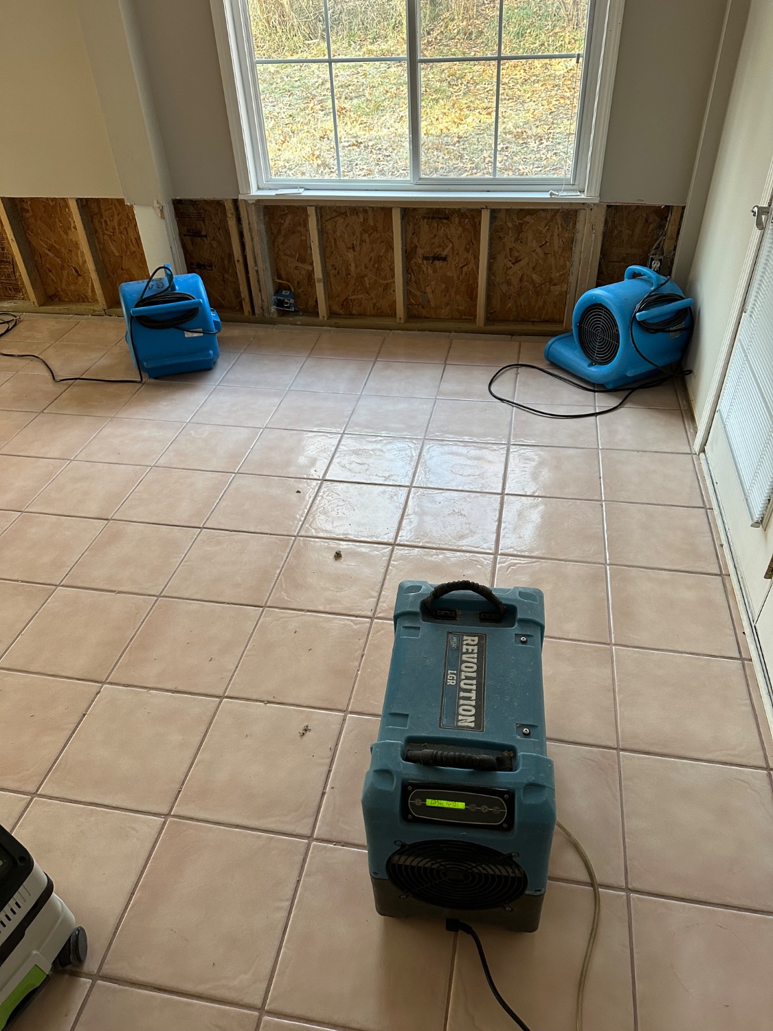 Water restoration in progress — air movers and an LGR dehumidifier drying a room with flood-cut walls