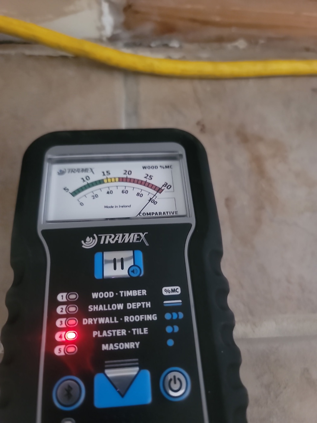 Tramex moisture meter reading moisture levels on a water-damaged wall